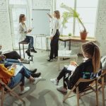 open-information-female-speaker-giving-presentation-hall-workshop-business-centre-rear-view-participants-audience-conference-event-training-education-diversity-inclusive-concept