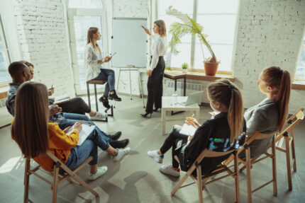 open-information-female-speaker-giving-presentation-hall-workshop-business-centre-rear-view-participants-audience-conference-event-training-education-diversity-inclusive-concept