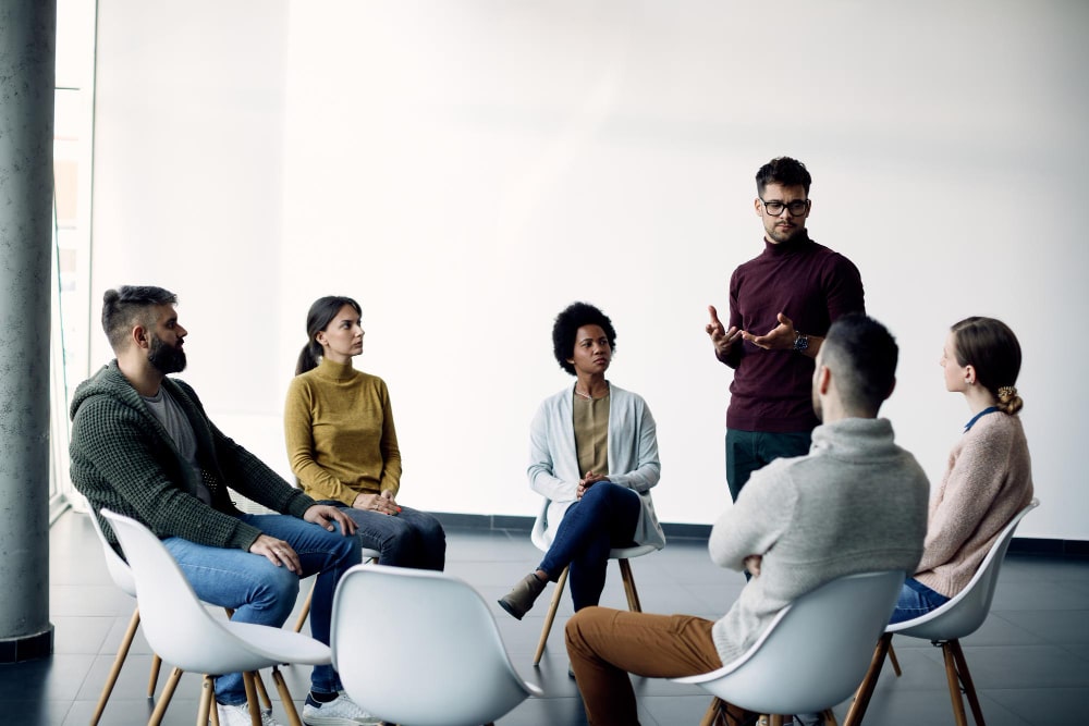 young-man-talking-about-his-problems-during-group-psychotherapy-min